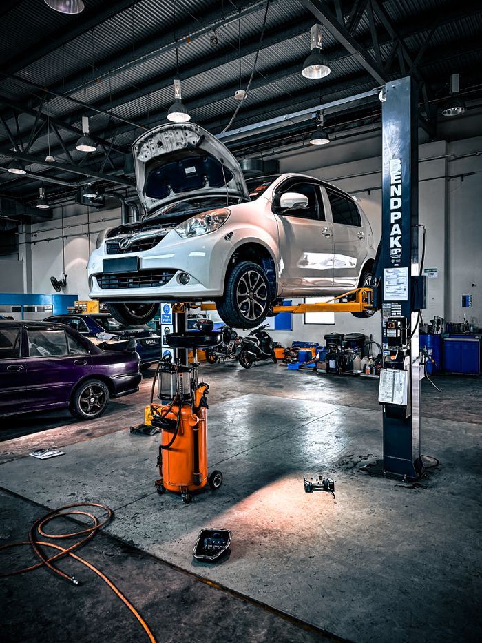 portfolio-02 A car is lifted on a hydraulic lift in a well-equipped auto repair shop.